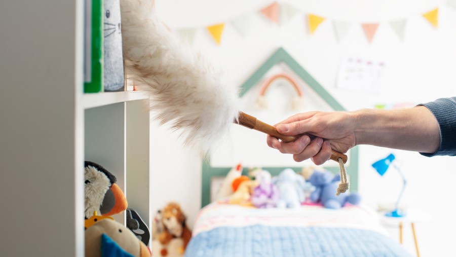 Eine Person wischt Staub aus den Regalen in einem Kinderzimmer. Eine Person wischt Staub aus den Regalen in einem Kinderzimmer.