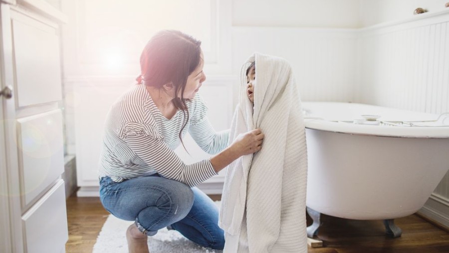 Mutter wickelt ihr Kind in Bademantel ein. Mutter wickelt ihr Kind in Bademantel ein.
