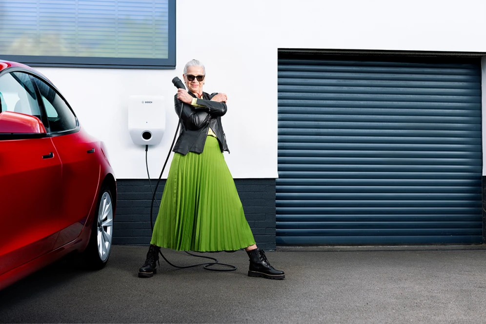 Frau steht neben Auto mit Wallbox