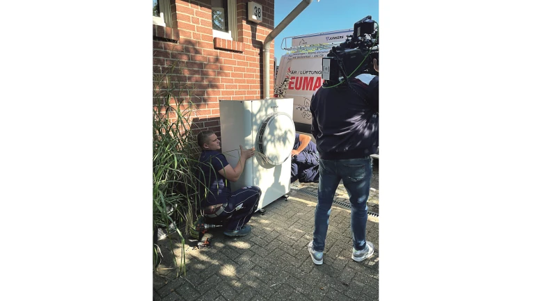 Wärmepumpe vor Backsteinhaus mit Kamerateam