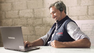 Bosch Service Mitarbeiter schaut in seinen Laptop und telefoniert mit einem Kunde. Bosch Service Mitarbeiter schaut in seinen Laptop und telefoniert mit einem Kunde.