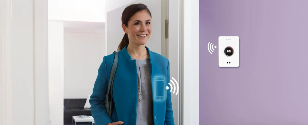 Frau bedient mit Smartphone den Easy Control von Bosch und verlässt das Haus.