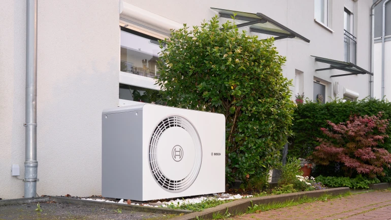 Bosch Wärmepumpe Compress 5800/6800i AW steht vor modernem Reihenhaus.