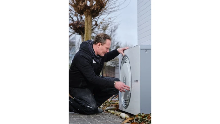 Ein Installateur arbeitet an einer Wärmepumpe im Garten.