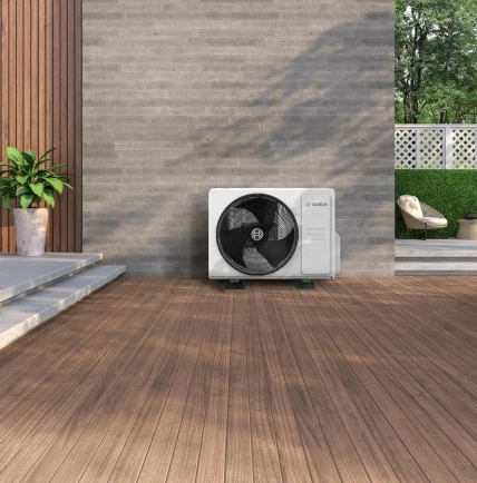 Ein Klimagerät steht an der Hauswand eines moderen Hauses.