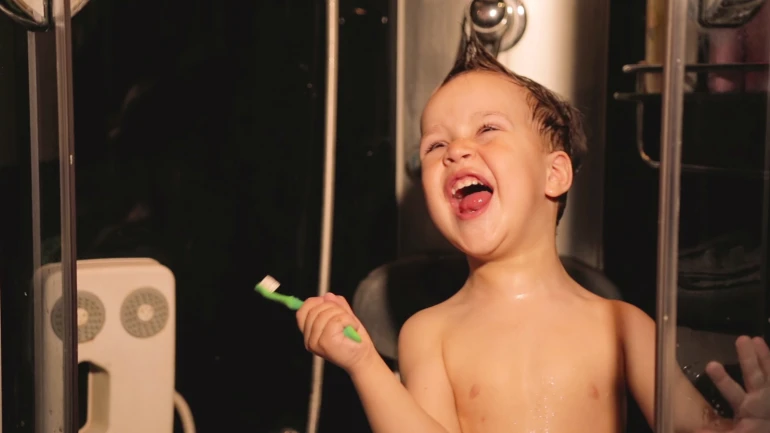 Kleiner Junge steht in der Deusche und singt.