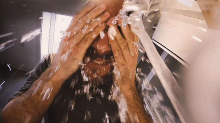 Ein Mann wäscht sich sein Gesicht, unter laufendem Wasserhahn.