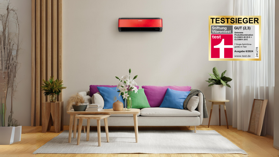 Über einer Couch hängt eine graue Klimaanlage. Recht sind die Testsiegersymbole zu sehen.
