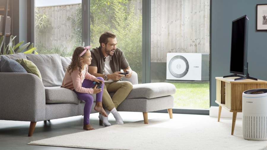 Familie im Wohnzimmer, auf der Terrasse steht die Compress 5800i AW von Bosch