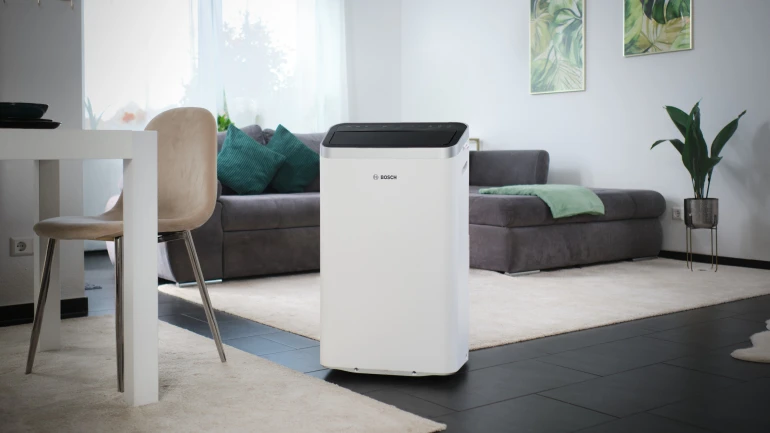 Ein mobiles Klimagerät von Bosch steht in einem Wohnzimmer.