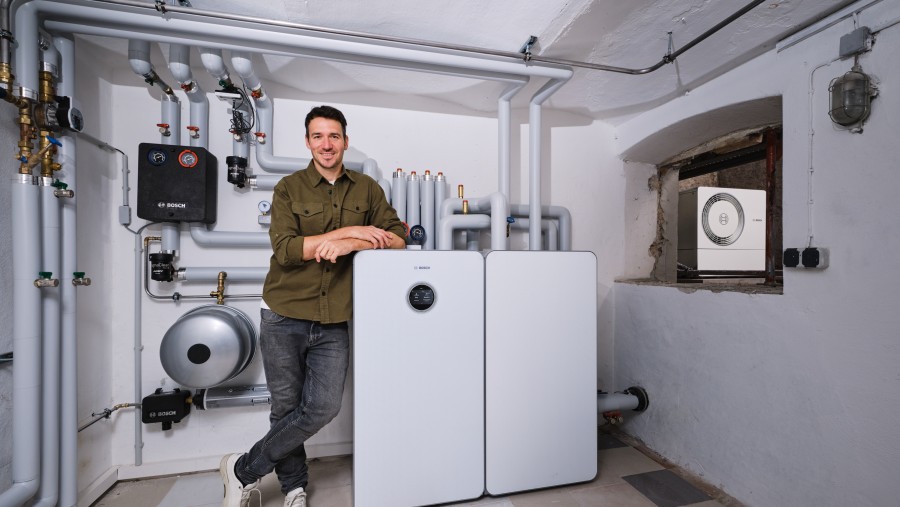Skirennläufer Felix Neureuther steht neben der Inneneinheit einer Wärmepumpe.
