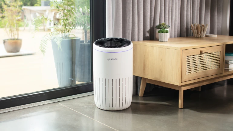 Ein Bosch Luftreiniger steht am Fenster eines Wohnzimmers.