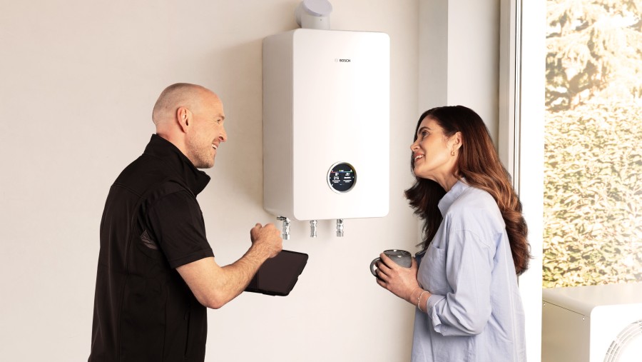 Ein Installateur und eine Frau stehen vor einem wandhängenden Gasbrennwertgerät und unterhalten sich. Ein Installateur und eine Frau stehen vor einem wandhängenden Gasbrennwertgerät und unterhalten sich.