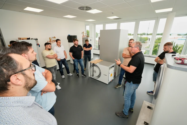 Mehrere Männer stehen in einem Kreis um eine Wärmepumpe 6800i AW herum.