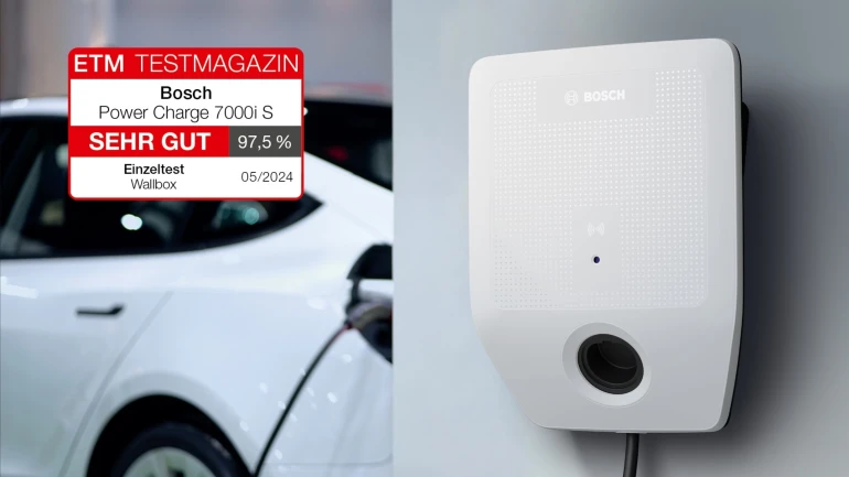 Wallbox von Bosch hängt an einer Wand, im Hintergrund steht ein Auto das aktuell geladen wird.