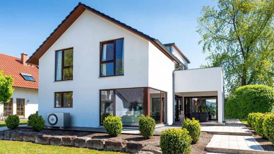 Ein modernes Haus mit einer Wärmepumpe davor. Ein modernes Haus mit einer Wärmepumpe davor.