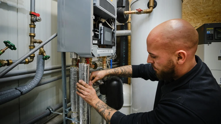 Mann mit schwarzem Pullover montiert eine Wärmepumpe.