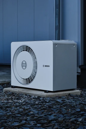 Eine Bosch Wärmepumpe steht im dunkeln da.