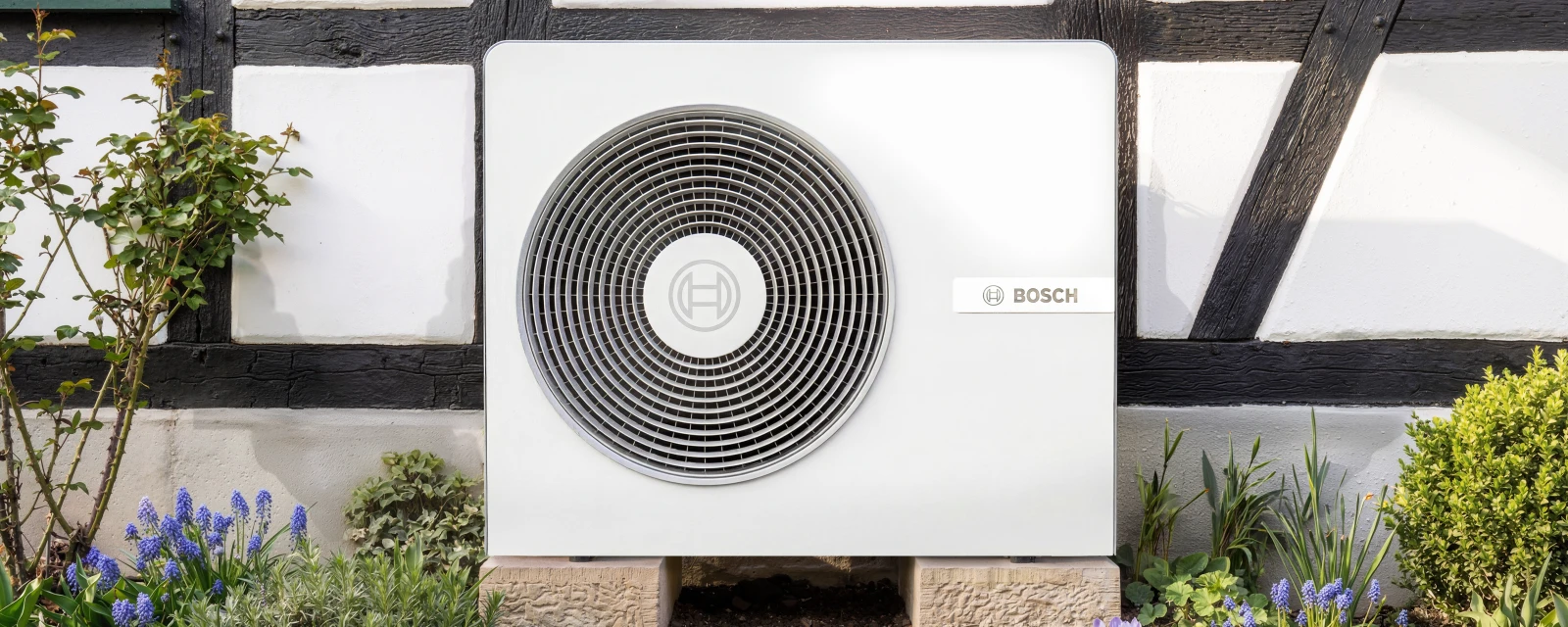 Die neue Wärmepumpe von Bosch steht an der Hauswand eines neuen Einfamilienhauses.