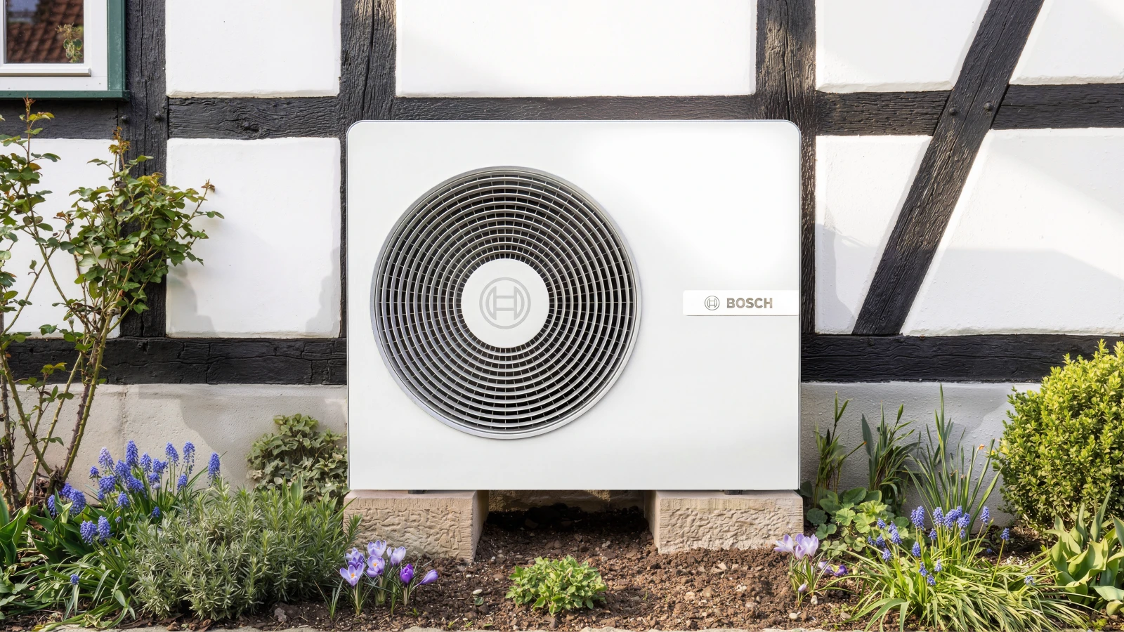 Außeneinheit der Bosch Luft-Wasser-Wärmepumpe Compress 8800i AW steht vor einem Fachwerkhaus