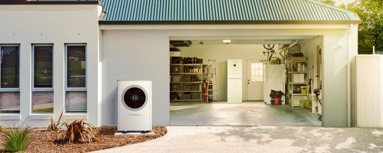 Vor einer Garage steht eine Wärmepumpe