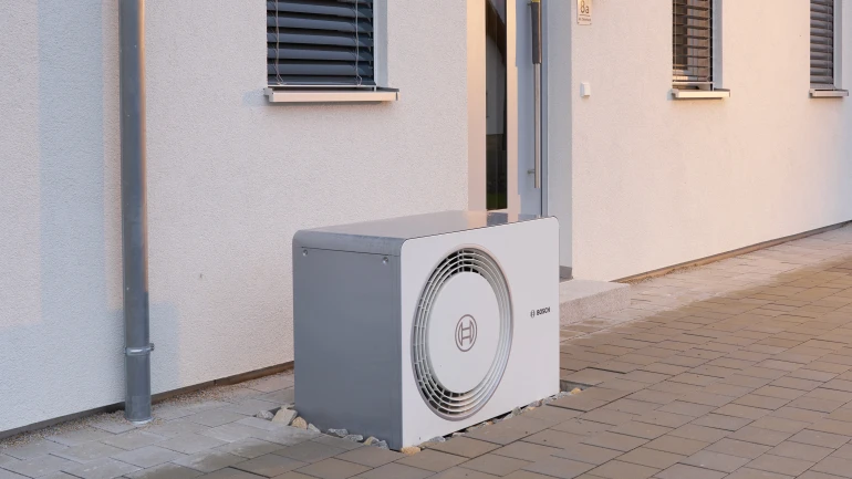 Außeneinheit Bosch Compress 5800i AW Wärmepumpe vor Neubauhauswand stehend