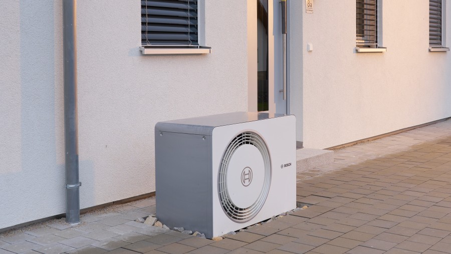 Außeneinheit Bosch Compress 5800i AW Wärmepumpe vor Neubauhauswand stehend Außeneinheit Bosch Compress 5800i AW Wärmepumpe vor Neubauhauswand stehend