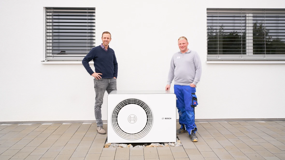 Zwei Männer stehe neben Bosch Wärmepumpe Compress 5800i AW