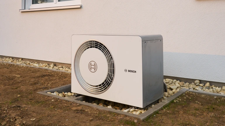 Bosch Wärmepumpe Compress 5800i AW vor einem Gebäude auf Fundament