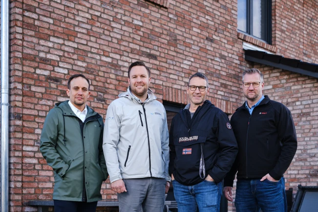 Vier Männer stehen vor einem Backsteinhaus.