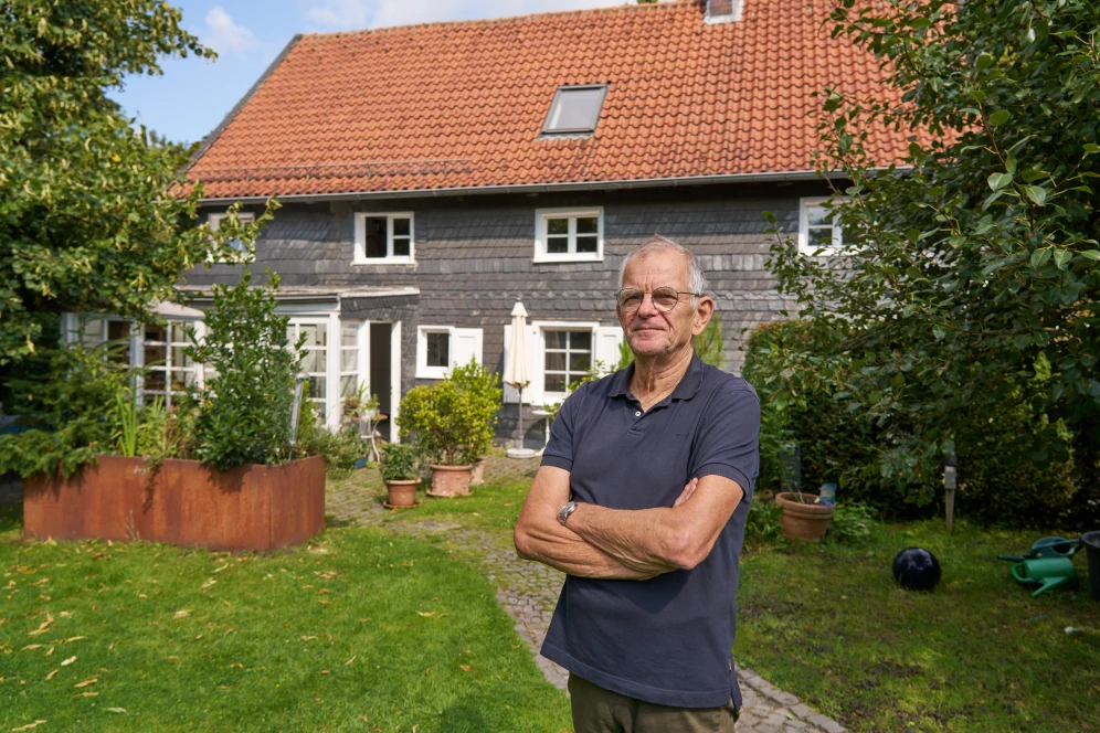 Bauherr mit alten Fachwerkhaus im Hintergrund