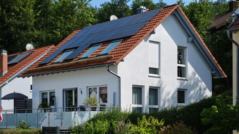 Ein weiß gestrichenes Haus mit Solarpaneelen auf dem Dach.