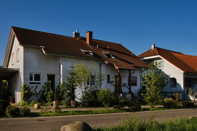 Die Wärmepumpe Compress 6800i AW vor Doppelhaushälfte im Garten stehend