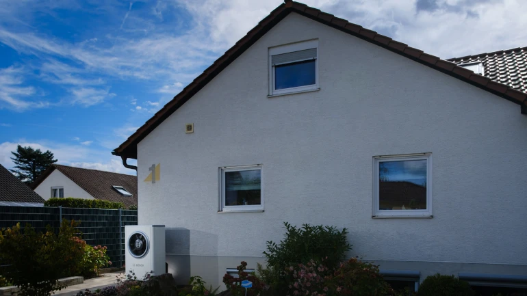 Eine Wärmepumpe Compress 7400i AW steht vor einem Einfamilienhaus.