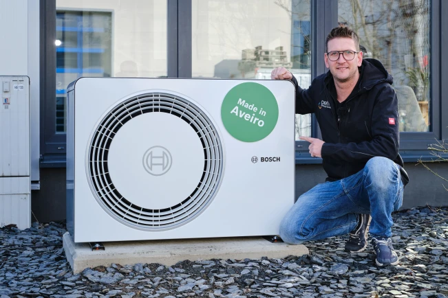 Mann kniet neben Bosch Wärmepumpe Compress 6800i AW