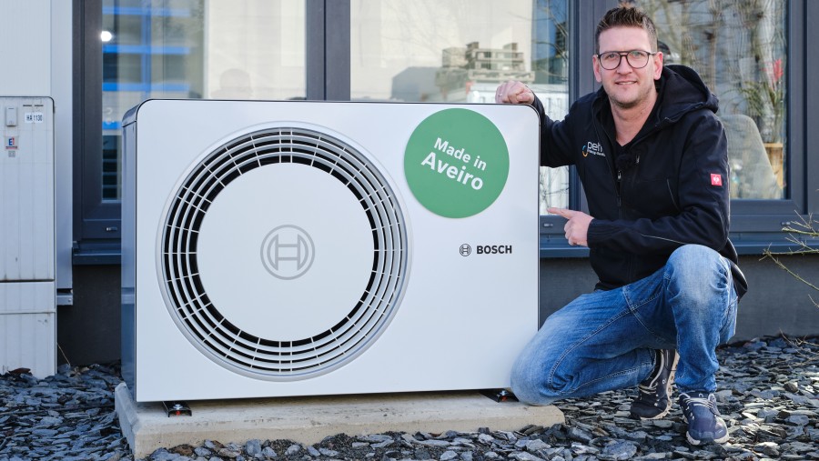 Mann kniet neben Bosch Wärmepumpe Compress 6800i AW Mann kniet neben Bosch Wärmepumpe Compress 6800i AW