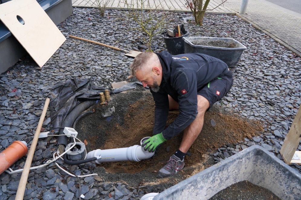 Mann arbeitet an Fundament für Wärmepumpe
