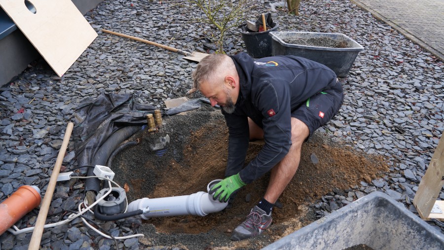 Mann arbeitet an Fundament für Wärmepumpe