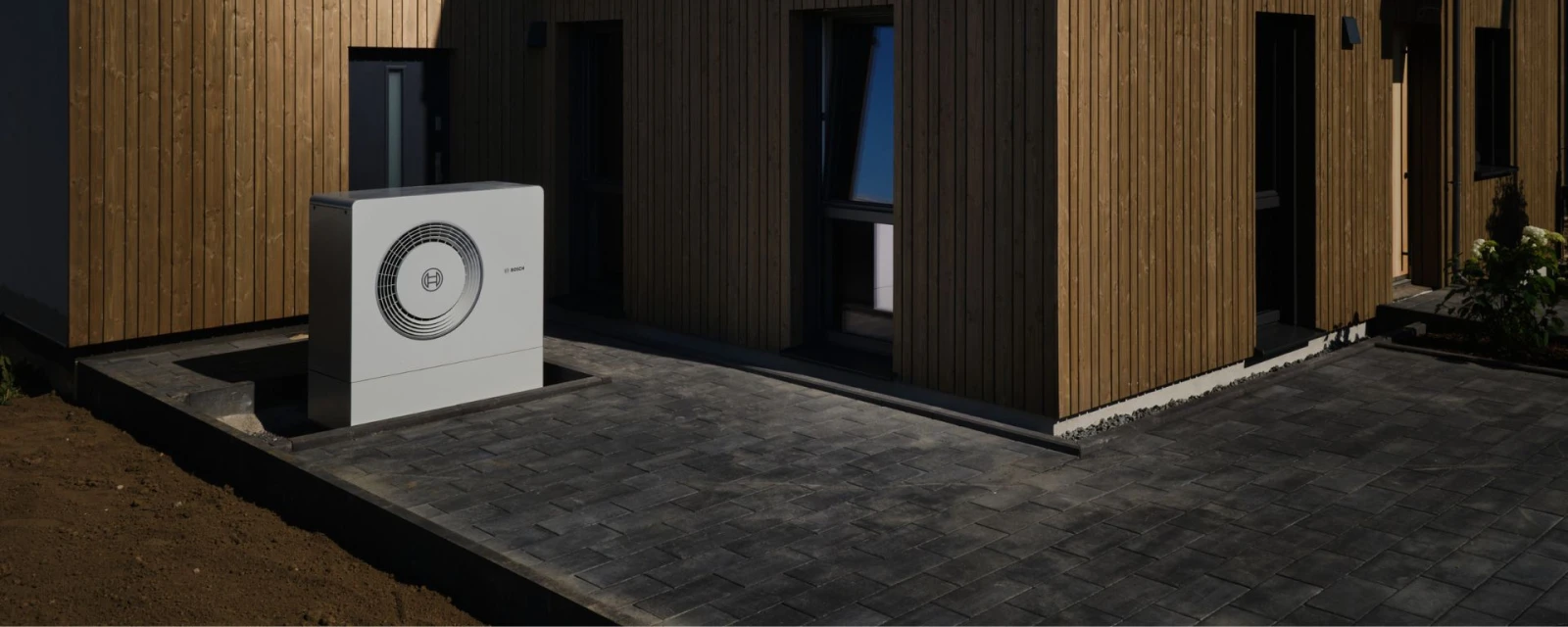 Ein Haus mit Wärmepumpe davorstehend.