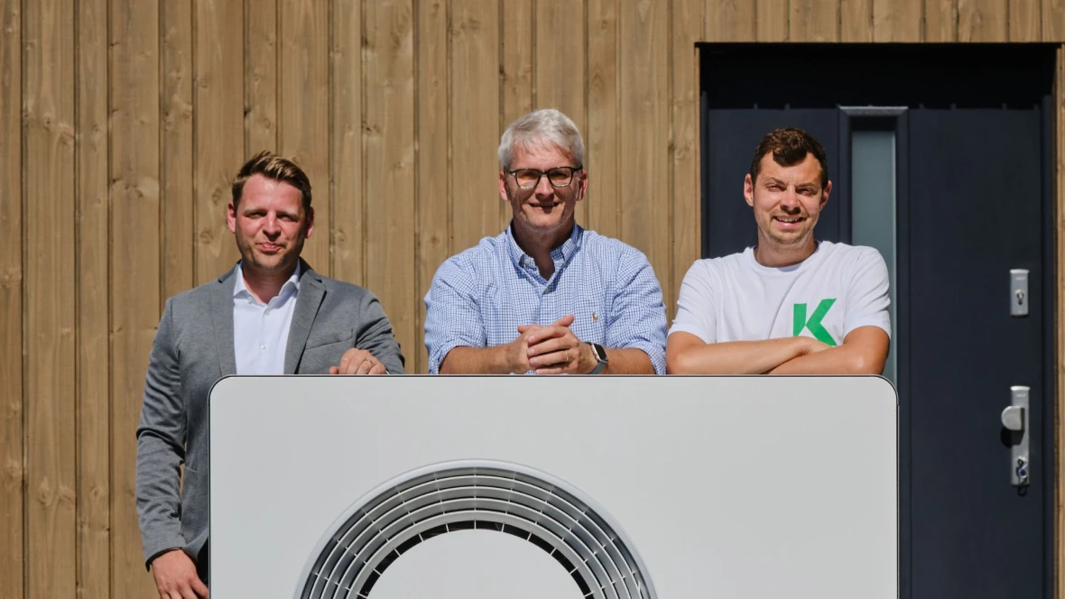 Mehrere Männer stehen hinter einer Wärmepumpe.