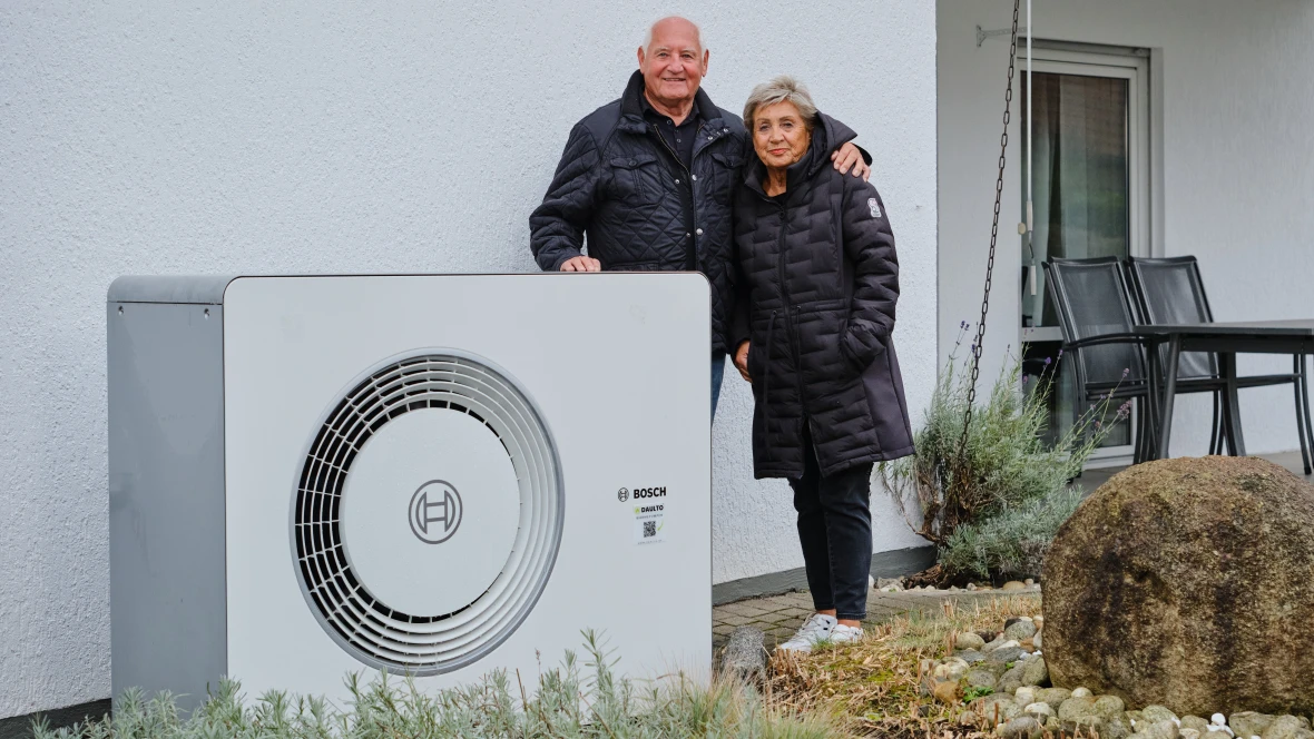 Eine Frau, ein Mann stehen hinter der Wärmepumpe Compress 6800i AW.