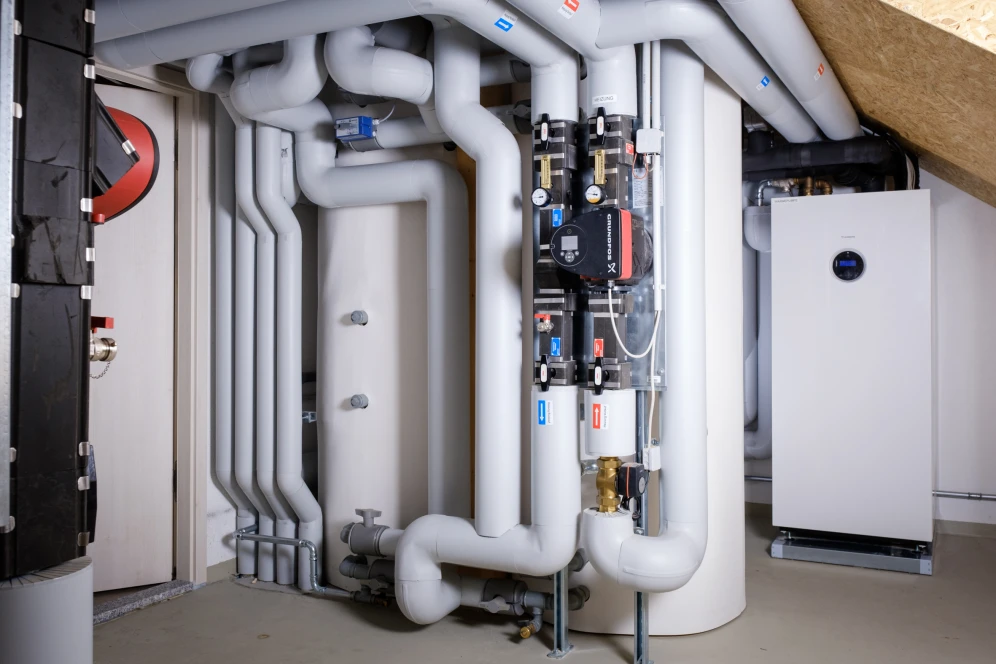 Moderne Anlagentechnik einer Großwärmepumpe im energieautarken Wohnquartier "Energieinsel in Petershagen". Ein zentraler Technikraum mit gut isolierten Rohrleitungen, Pumpensystem und leistungsstarker Wärmepumpeneinheit.