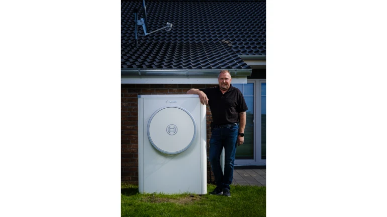 Installateur steht neben der Wärmepumpen Außeneinheit der Compress 7400i AW