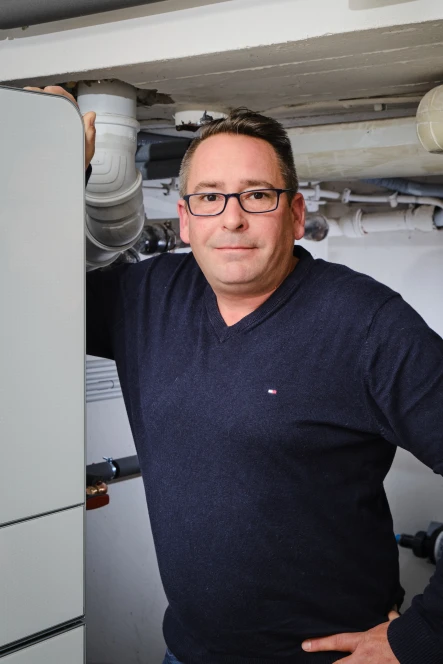 Mann lehnt an Wärmepumpen Inneneinheit