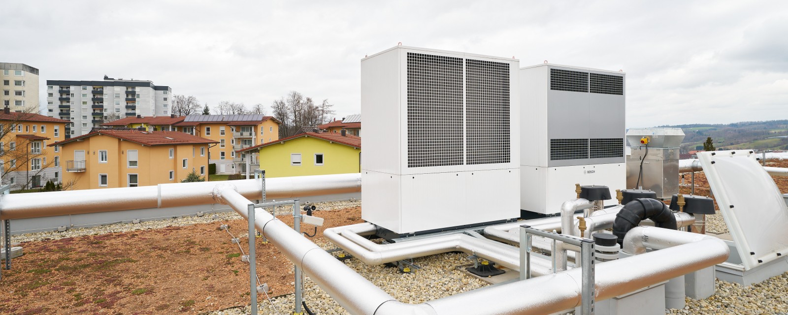 Bosch Compress 5000 AW Monoblock Luft-Wasser-Wärmepumpe in Kaskadenschaltung stehen auf einem Hausdach Bosch Compress 5000 AW Monoblock Luft-Wasser-Wärmepumpe in Kaskadenschaltung stehen auf einem Hausdach