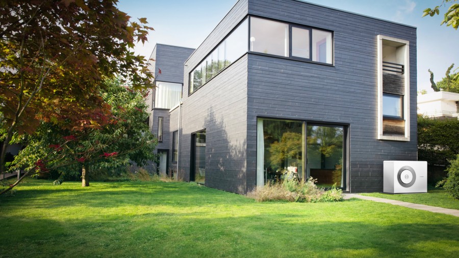 Eine Bosch Wärmepumpe Compress 5800i AW steht an Hauswand eines Einfamilienhauses mit großem Garten. Eine Bosch Wärmepumpe Compress 5800i AW steht an Hauswand eines Einfamilienhauses mit großem Garten.