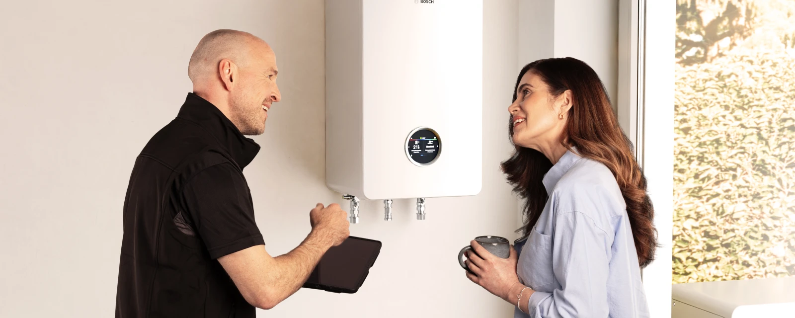 Installateur und Frau stehen vor einem Hybridsystem.