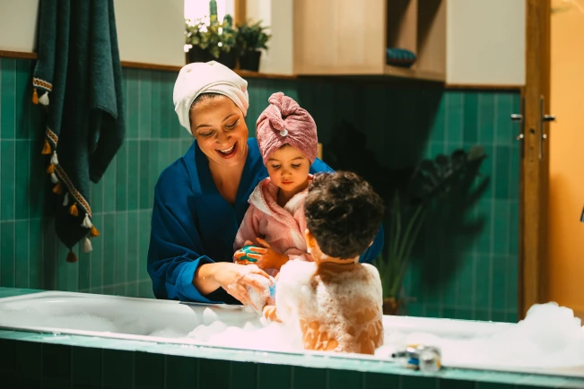 Eine Frau und zwei Kinder befinden sich im Badezimmer.