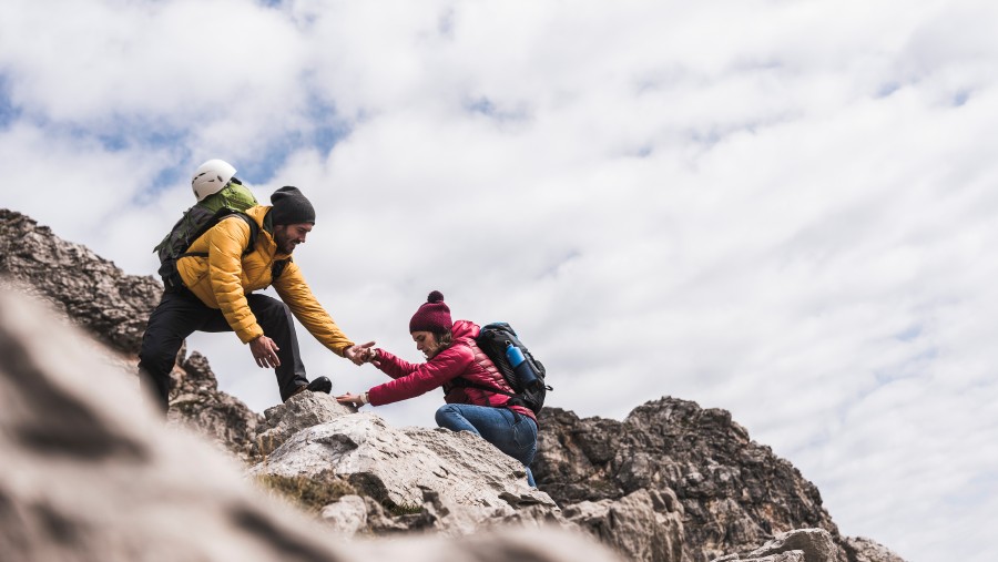 Ein Mann unterstützt eine Frau beim Bergsteigen. Ein Mann unterstützt eine Frau beim Bergsteigen.
