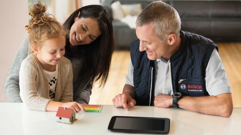 Eine junge Frau mit Kind spricht mit einem Wärmepumpen-Fachmann von Bosch.